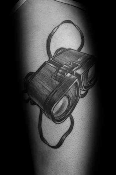 Black and grey binoculars tattoo with a realistic design and strap detail, creating a bold and adventurous look.