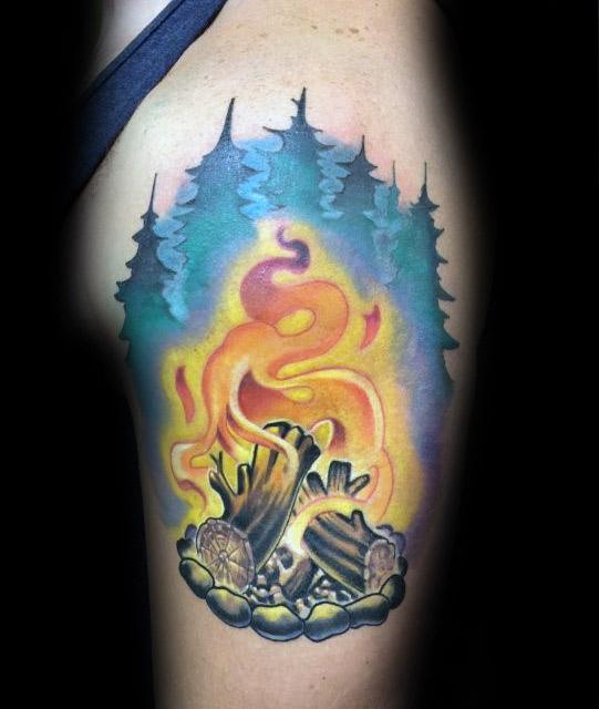 Colorful campfire tattoo with swirling flames, glowing smoke, pine tree silhouettes, and a stone fire ring on the upper arm.