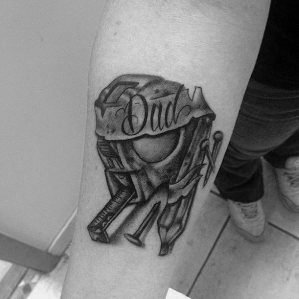 Black and gray tattoo of a carpenter's helmet with tools and "Dad" inscribed, symbolizing craftsmanship, hard work, and a tribute to a father.