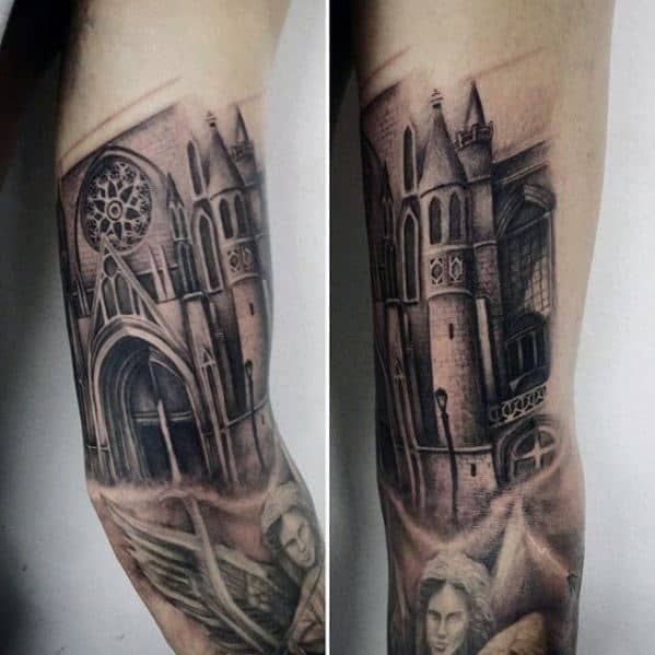 Forearm tattoo of a gothic cathedral with a large rose window and detailed towers, featuring angels and dramatic shading throughout.