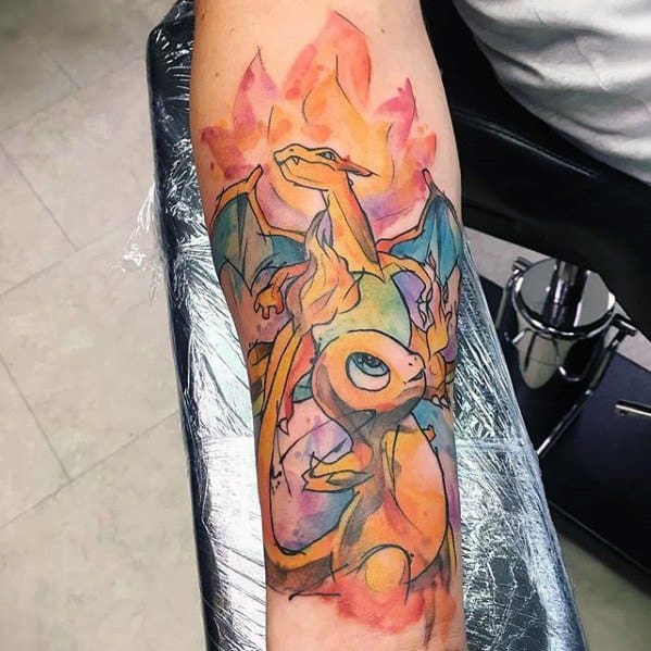 Watercolor-style tattoo of Charmander and Charizard with soft pastel tones and fluid linework, creating a dreamy fire-themed design on the forearm.