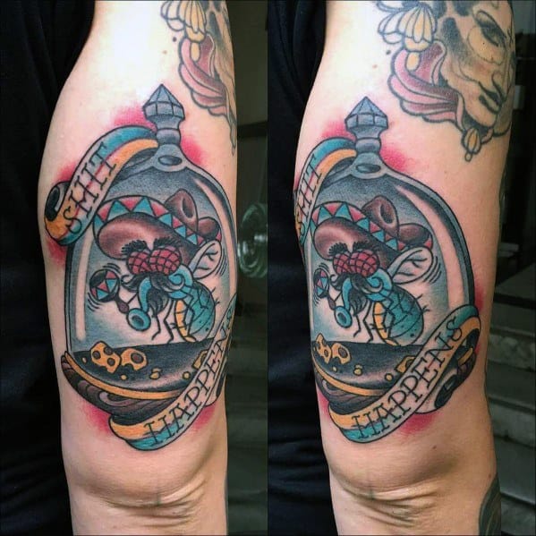 Colorful tattoo of a fly trapped under a glass dome with a wedge of Swiss cheese, featuring a banner that reads "Shit Happens," bold outlines, and vibrant shading.