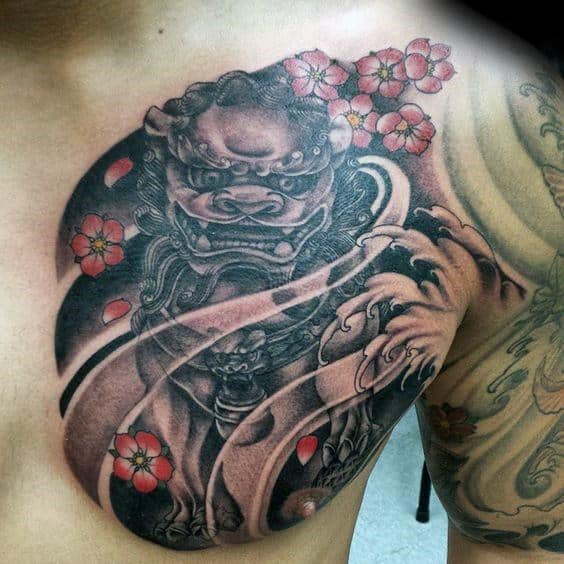 Japanese-style chest tattoo featuring a fierce Fu Dog guardian, swirling wind patterns, and vibrant pink cherry blossoms with falling petals