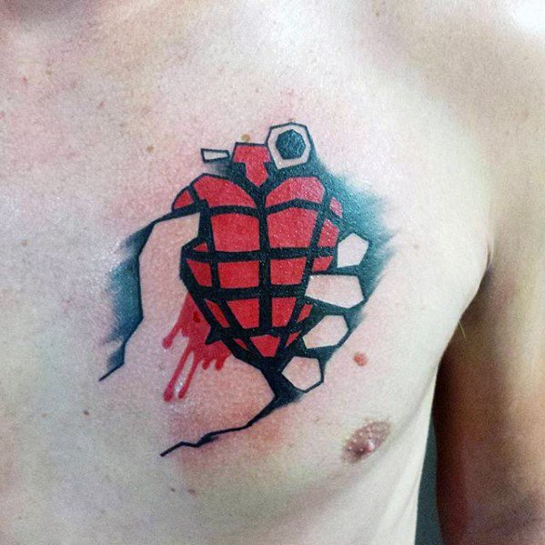 Chest tattoo of a hand gripping a red heart-shaped grenade with dripping blood, inspired by Green Day’s *American Idiot* album cover.