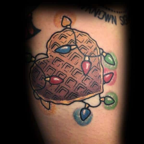 Christmas tattoo of a heart-shaped waffle wrapped in colorful holiday lights, combining festive cheer with a fun and unique food-inspired design.