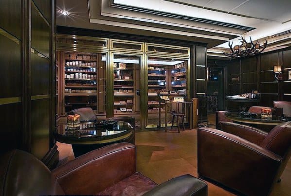Cozy cigar lounge with leather chairs, a glass-enclosed humidor, dim lighting