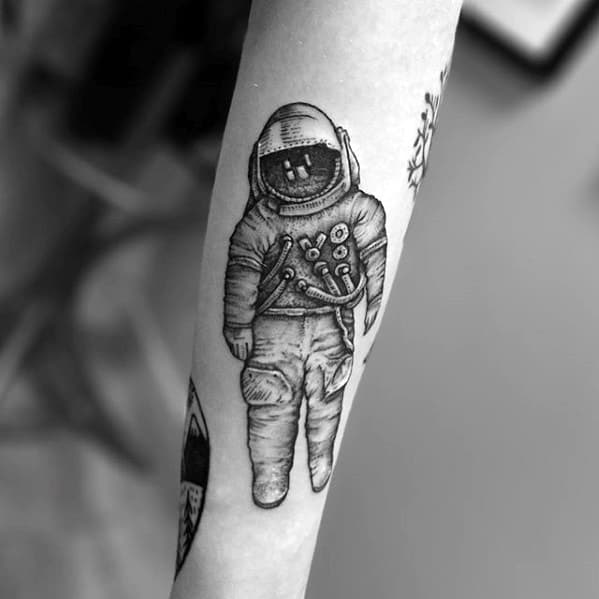 Fine line blackwork Deja Entendu astronaut tattoo on forearm with minimal shading and a vintage illustrative style.
