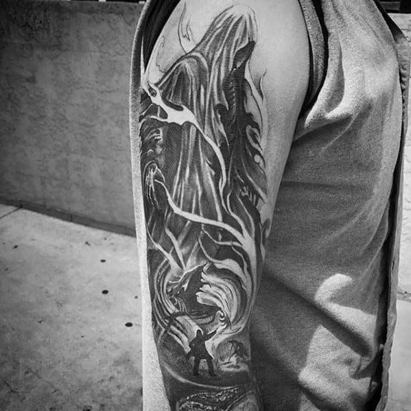 Full upper arm tattoo in black and grey showing a massive Dementor looming over Harry Potter as he casts a Patronus spell below.