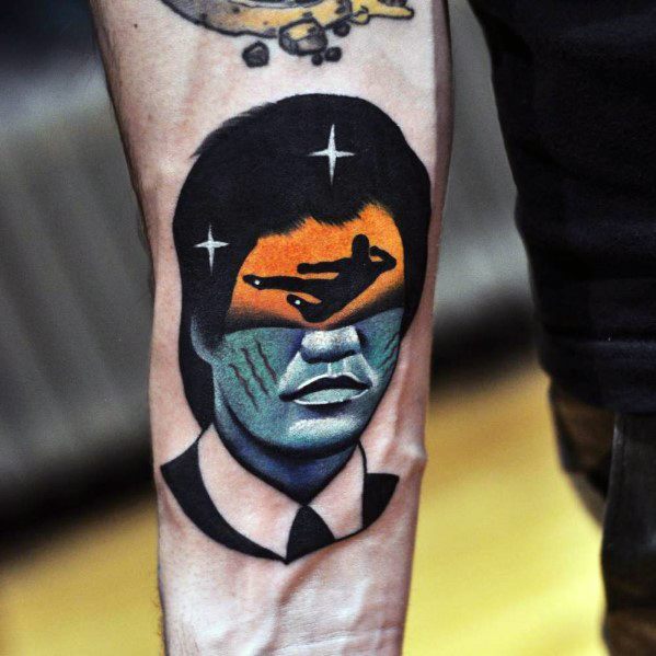 Surreal tattoo of a suited man's portrait with a cosmic face, featuring a flying plane and colorful landscape blending into abstract elements.