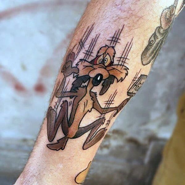 Color tattoo of Wile E. Coyote falling in classic cartoon style, with motion lines emphasizing the dramatic descent on the forearm.