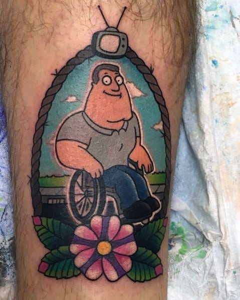 Tattoo of Joe Swanson from Family Guy in a traditional-style framed design, sitting in his wheelchair with a smile, surrounded by floral and rope details.