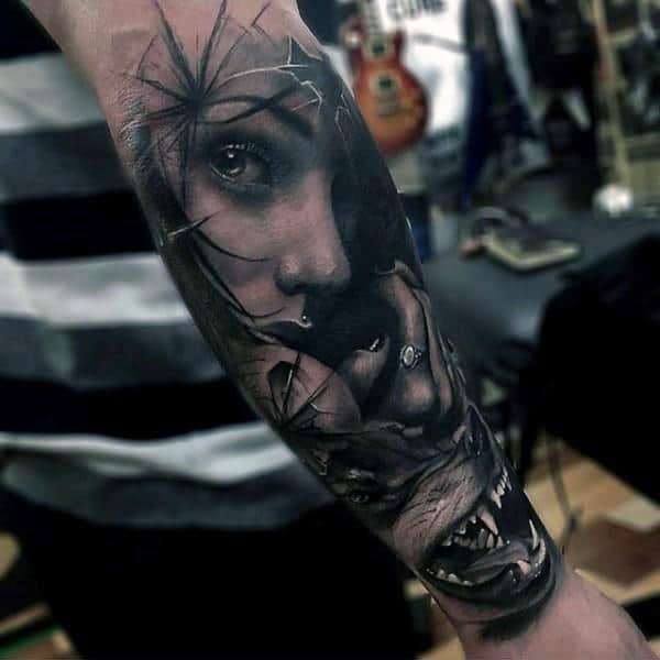 Forearm tattoo of a woman's face merging with a snarling wolf, surrounded by a shattered glass effect