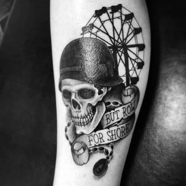 Black and grey Ferris wheel tattoo featuring a detailed skull wearing a helmet, a banner reading "But row for shore," and a nautical chain for a bold design.