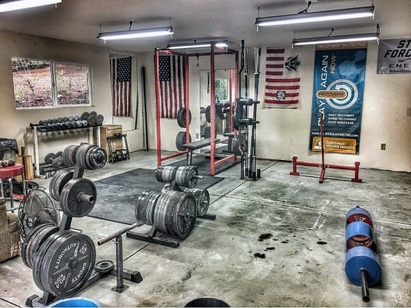 Garage gym featuring weights, power rack, bench press, and American flag decor.