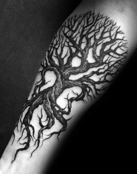 Black and grey forearm tattoo featuring a twisted, leafless tree with intricate branches and deep roots, creating a dark and gothic aesthetic.