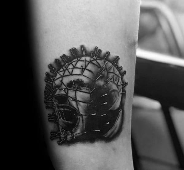 Black and grey *Hellraiser* tattoo of Pinhead screaming, featuring intricate pin details, deep shading, and a dark, intense horror aesthetic.