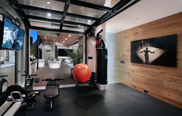 Modern home gym with exercise equipment, a punching bag, and a large glass door leading to an outdoor seating area