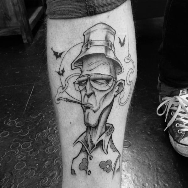 Black and white Hunter S. Thompson tattoo featuring a stylized caricature with exaggerated features, aviator glasses, a bucket hat, a cigarette, and bats.