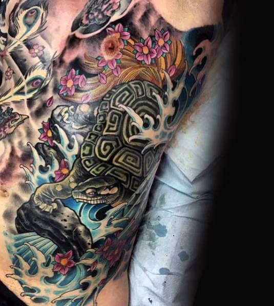 Japanese-style chest tattoo featuring a fierce turtle, crashing waves, cherry blossoms, and bold shading, symbolizing resilience and longevity.