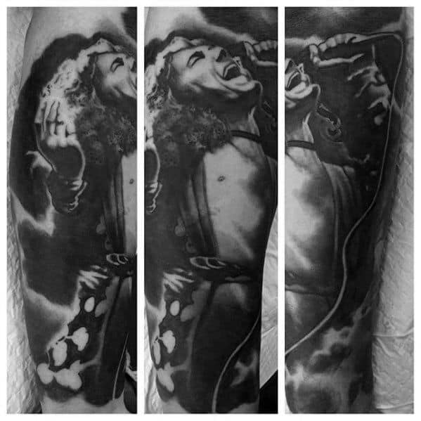 Black and gray tattoo sleeve of Robert Plant passionately singing into a microphone, with dramatic lighting and smoky background effects.