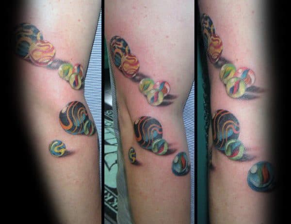 Vibrant 3D tattoo of colorful marbles cascading down the arm, creating a dynamic and realistic effect with bold shading and reflections.