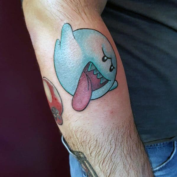 Mario ghost tattoo featuring Boo with a playful expression, tongue out, and blue shading, inked on the forearm with a bold outline.