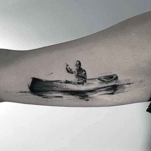 Realistic black and grey tattoo of a man paddling a canoe on calm water, symbolizing solitude, adventure, and a deep connection with nature.