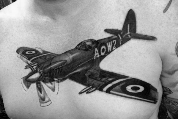 Realistic black and grey chest tattoo of a WWII fighter plane in flight, featuring intricate shading, motion blur on the propeller, and bold details.