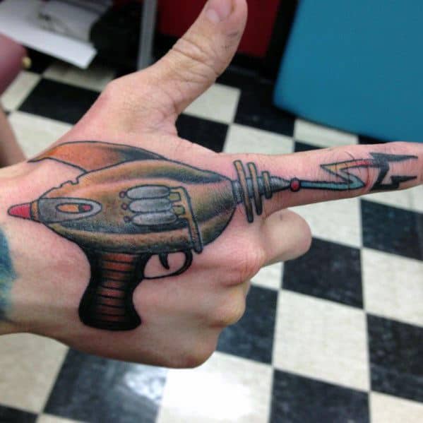 Creative ray gun tattoo spanning the hand and finger, designed to align with the thumb for a fun, interactive retro sci-fi effect.
