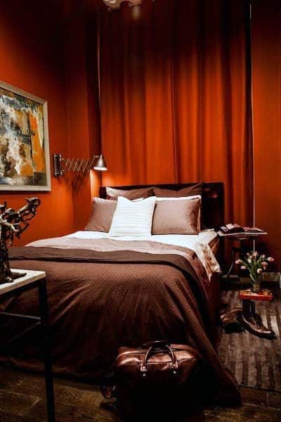 Luxury bedroom with red curtains, brown bedding, and modern artwork.