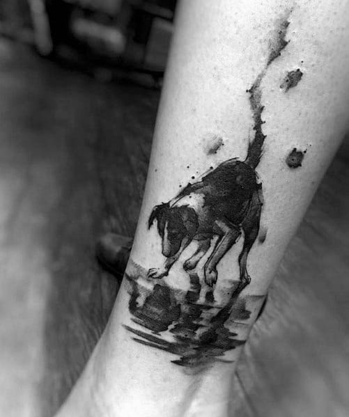 Tattoo of a dog curiously looking into its reflection in the water, featuring a watercolor effect and paw prints for a dynamic, artistic touch.