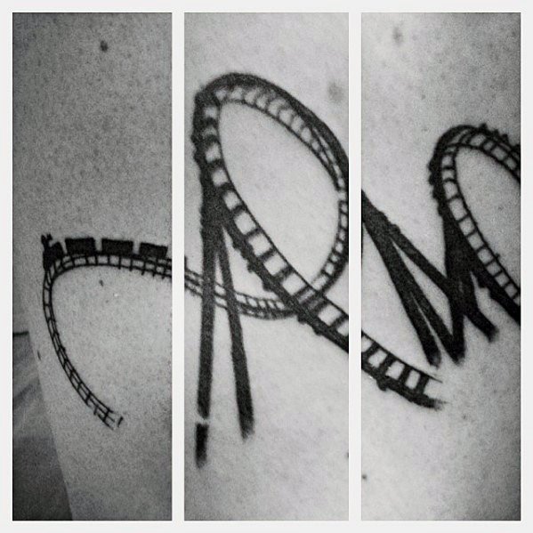 Black ink roller coaster tattoo wrapping around the body with sharp loops and a tiny train car in motion on the track.