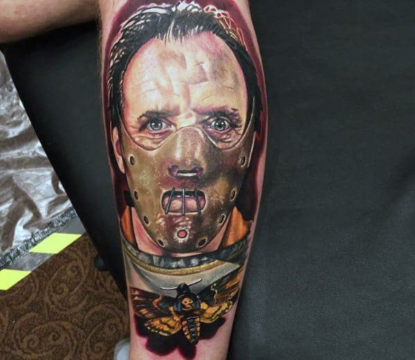 Realistic color tattoo of Hannibal Lecter from *The Silence of the Lambs*, featuring his iconic muzzle and a death’s-head moth for a chilling horror design.