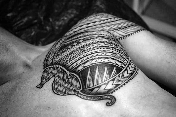 Polynesian-style seahorse tattoo on chest and shoulder, featuring bold black tribal patterns with intricate geometric details for a powerful look.