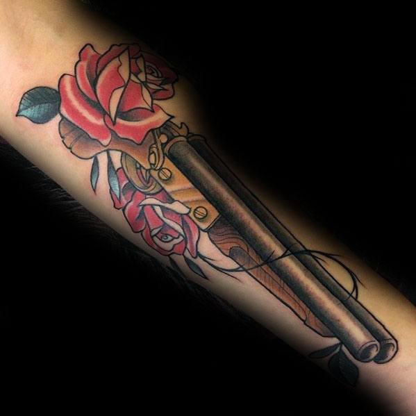 Elegant shotgun tattoo on the forearm with red roses entwined around the barrel, blending bold firepower with delicate floral artistry.