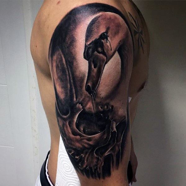 Dark surreal swan tattoo on upper arm, featuring a dripping black swan above a skull, blending beauty with a haunting, gothic aesthetic.