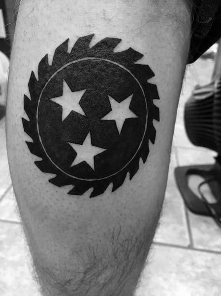 Black and grey Tennessee three-star emblem tattoo with a saw blade border, symbolizing strength, resilience, and state pride.