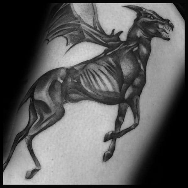 Sleek Thestral tattoo in black and grey realism, showing defined muscles and wings mid-motion on the outer arm.