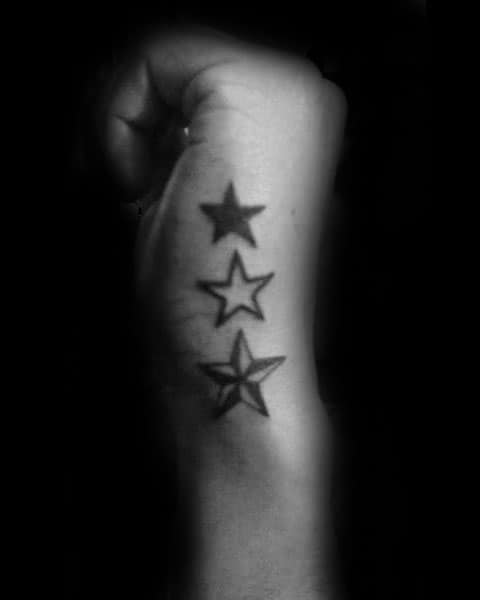 Side hand tattoo for men with three bold stars in a vertical line, featuring both solid and outlined styles.