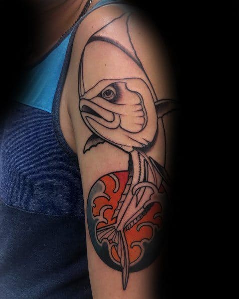 Stylized tuna fish skeleton tattoo on a man's upper arm, featuring bold outlines, minimal shading, and a vibrant red circular background.