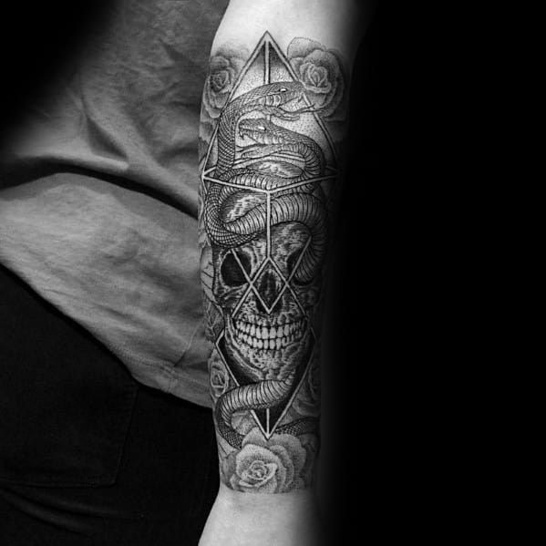 Black and grey two-headed snake tattoo on the forearm, intertwined with a skull, geometric shapes, and roses for a dark and intricate design.