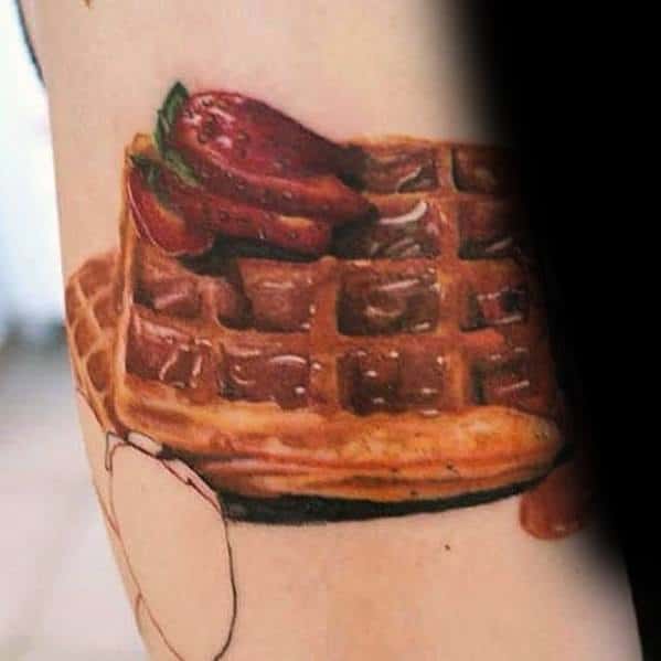 Realistic waffle tattoo with rich shading, topped with sliced strawberries and syrup, creating a detailed and appetizing breakfast-inspired design.