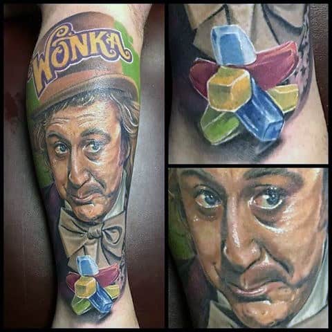 Colorful Willy Wonka tattoo with a mischievous expression, Wonka text on the hat, and vibrant candy shapes below the portrait.