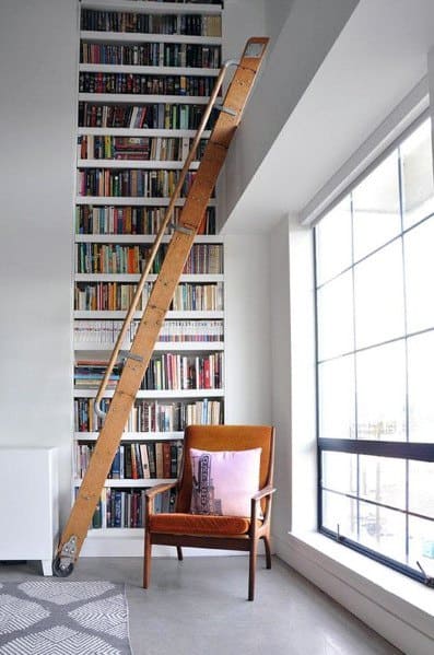 Cozy room: tall bookshelf with ladder, armchair, and large window