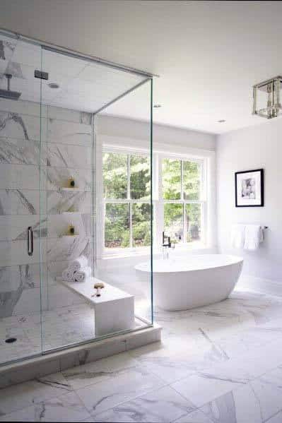 Modern white bathroom with a glass shower, freestanding tub, and large window