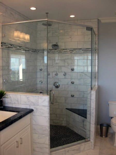 Modern bathroom with a corner glass-enclosed shower and marble tiles, featuring multiple showerheads