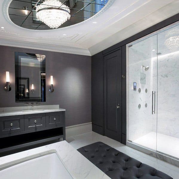 Luxury master bathroom with black vanity, glass shower, crystal chandelier, and marble finishes.