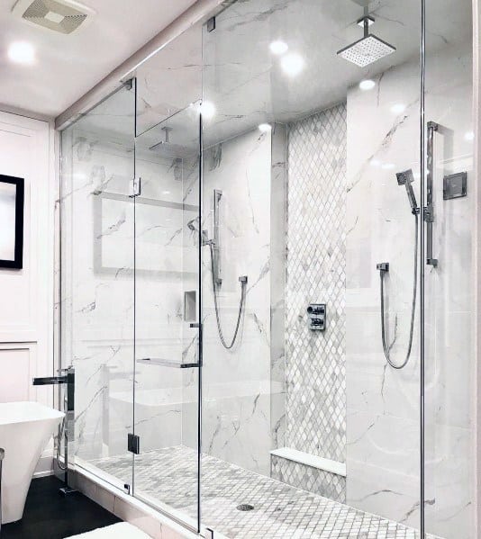 Luxurious master bathroom shower with marble walls, sleek glass enclosures, dual showerheads, and soft recessed lighting for a sophisticated look