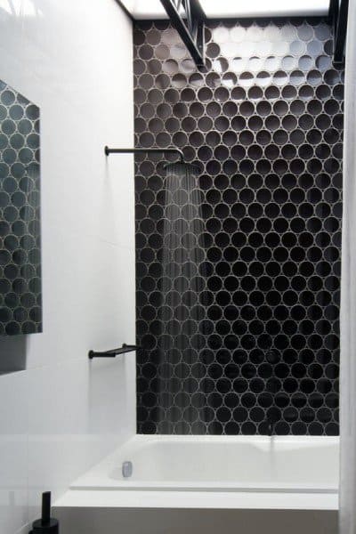 Black 3D decorative tile shower wall with white bathtub and matte black fixtures.