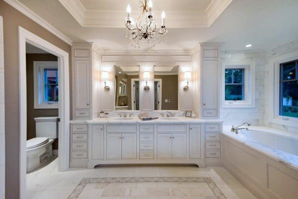 Luxurious master bathroom with a trey ceiling, crown molding, elegant chandelier, and a spacious vanity area